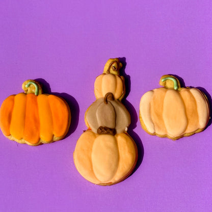 Three pumpkin-shaped cookies on a purple background