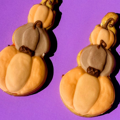 Pumpkin-shaped earrings on a purple background