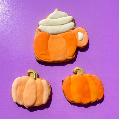 Pumpkin-shaped cookies with white frosting on a purple background