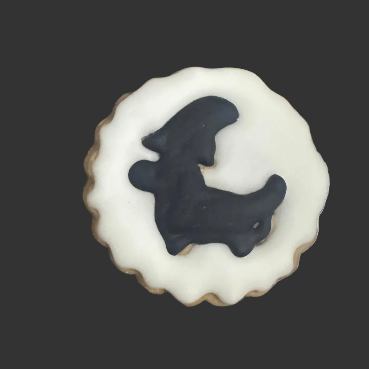 A round white-frosted cookie with a black silhouette of a dachshund 