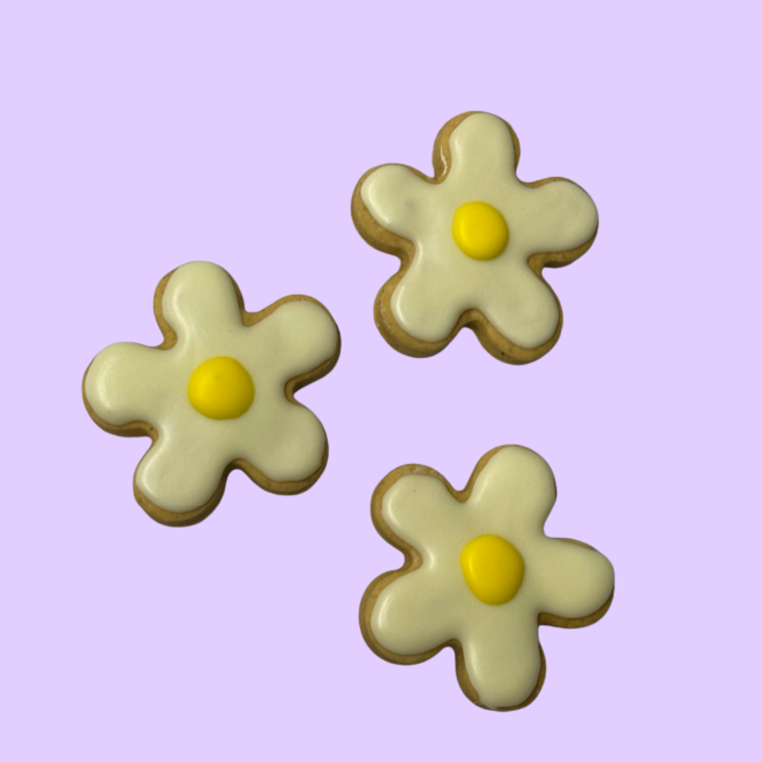 Three flower-shaped cookies with yellow centers on a purple background