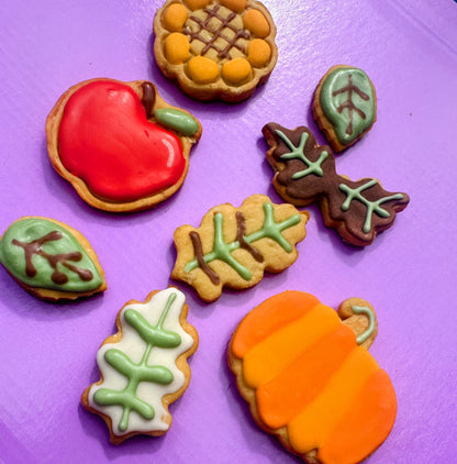 Decorative cookies shaped like an apple, leaf, and pumpkin on a purple background