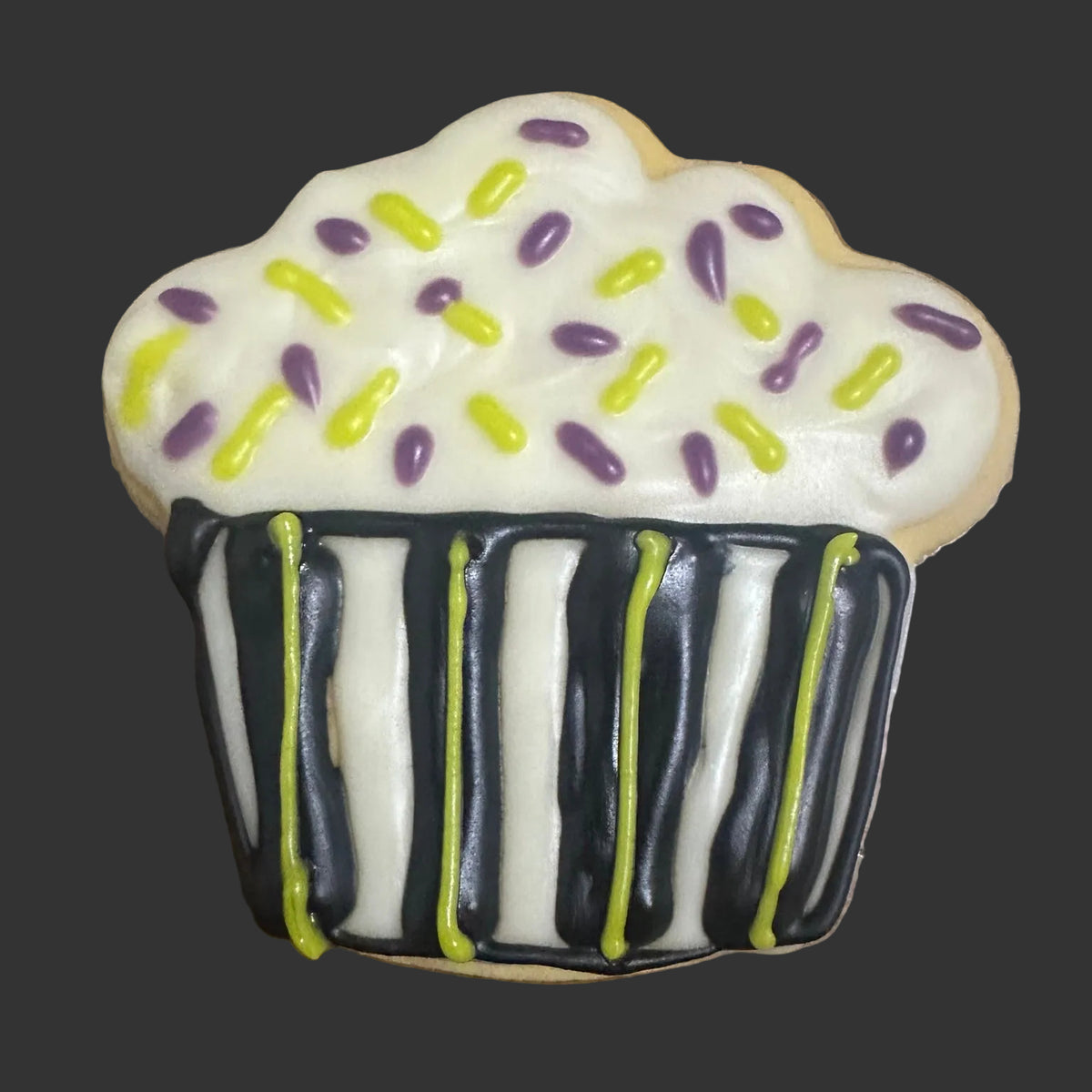 Halloween dog biscuit shaped like a cupcake with black, white and green icing and purple and green sprinkles.