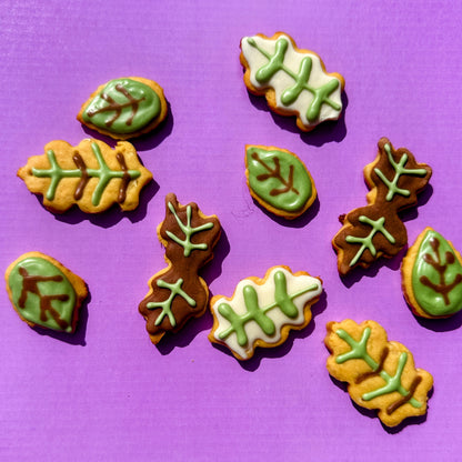 Leaf-shaped cookies with green icing on a purple background