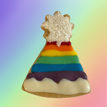 A dog biscuit shaped like a party hat, decorated with rainbow colors and a white icing resembling a cloud on top.