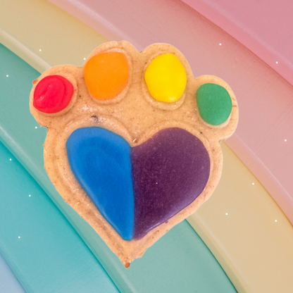 Colorful paw-shaped cookie with a heart in the center on a pastel background decorated in the rainbow colours