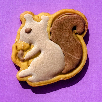 Squirrel-shaped cookie with white body and brown back on a purple background