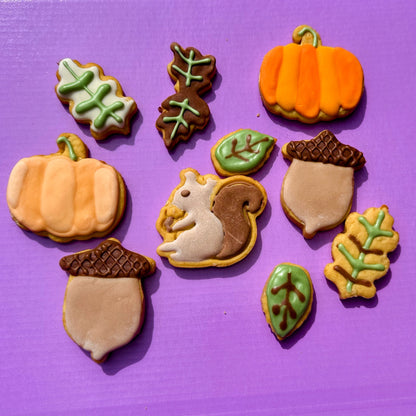 Decorative cookies shaped like pumpkins, acorns, and leaves on a purple background