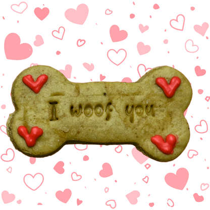A bone-shaped dog biscuit with 'I woof you' written on it and decorated with red love hearts.